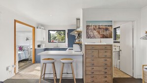 Una cocina moderna con encimera blanca, taburetes de madera y horno integrado.