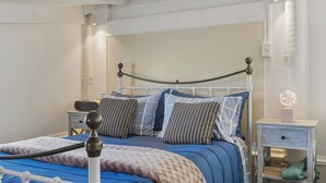 A bed with a metal frame, a bedside table with a lamp, and a wall-mounted light fixture.