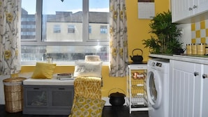 A compact kitchen with a window, washing machine, and a small dining area with a bench. - Mother of Stockton (Stockton-on-Tees)