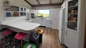 Une cuisine moderne dotée d’une verrière, de meubles blancs, d’un réfrigérateur encastré et d’un coin bar avec des tabourets.
