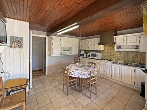 A kitchen with white cabinets, a dining table with a floral tablecloth, and a wooden ceiling.