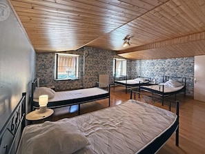 A room with three beds, wooden flooring, and a sloped ceiling. - Charming countryside house with peaceful garden, pets allowed (Saint-Victor-sur-Rhins)