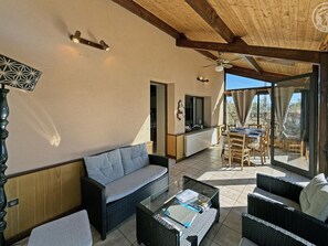 A sunlit patio with wicker furniture, a ceiling fan, and a view of the outdoors. - Charming countryside house with peaceful garden, pets allowed (Saint-Victor-sur-Rhins)
