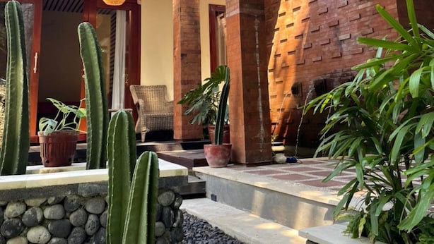 A modern house with a wooden roof, a brick wall, and a stone pathway. - Pandawa Villa Riverside by WizZeLa (Tabanan)