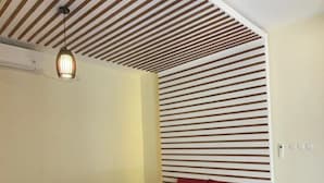 A modern bedroom with a slatted ceiling design, a wooden bed frame, and a red bedspread. - Pandawa Villa Riverside by WizZeLa (Tabanan)