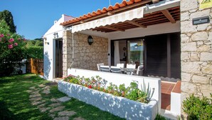 A modern house with a stone exterior, a tiled roof, and a patio with outdoor furniture.