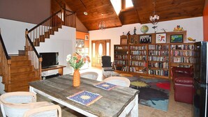 Un escalier en bois, une table à manger avec des chaises, une bibliothèque et un téléviseur.