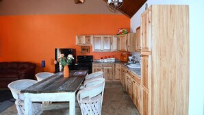 Une cuisine avec des meubles en bois, une table à manger avec des chaises et un lustre.