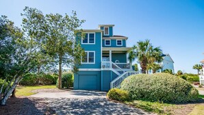 A two-story house with a blue exterior, a front porch, and a driveway. - Coastal Retreat at The Rookery: 4 BDRM Home (Pawleys Island)