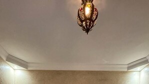A bedroom with a large bed, a nightstand, a lamp, a painting on the wall, and a radiator. - Charming villa with pool 8 km from Essaouira (Essaouira)