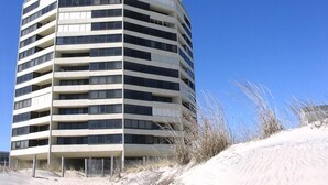 A multi-story building with a curved facade, featuring a series of balconies and windows. - Beautiful sunset and ocean view from 2 Bedroom Condo with Free WiFi and an Outdoor Pool Located in Midtown Only Steps to Beach! Vacation at the Shore with Shoreline Properties (Ocean City)