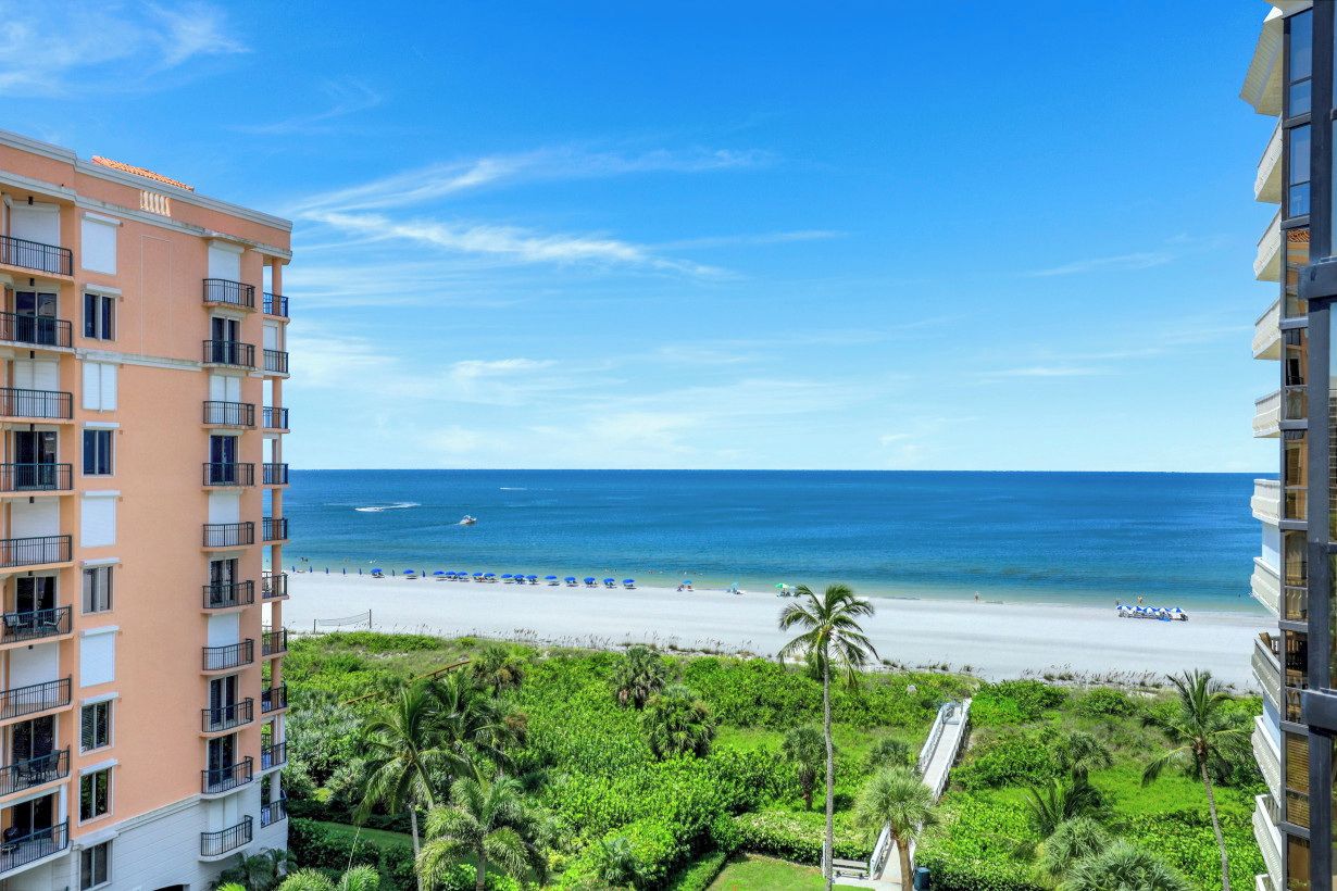 A high-rise hotel overlooking a beach with a clear view of the ocean and a sandy shoreline.