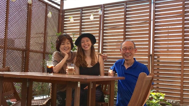 A wooden outdoor seating area with a table and chairs, surrounded by a wooden fence and a pergola with string lights. - Y's B&Kitchen Tokyo HY1 (Tokyo)