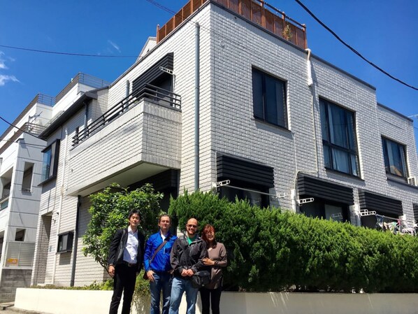 A modern multi-story building with a brick facade, balconies, and large windows. - Y's B&Kitchen Tokyo HY1 (Tokyo)