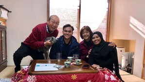 A group of people around a table with a red floral tablecloth, a laptop, and various items on the table. - Y's B&Kitchen Tokyo HY1 (Tokyo)