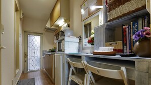 A narrow kitchen with wooden flooring, a white refrigerator, and a dining area with white chairs. - Y's B&Kitchen Tokyo HY1 (Tokyo)