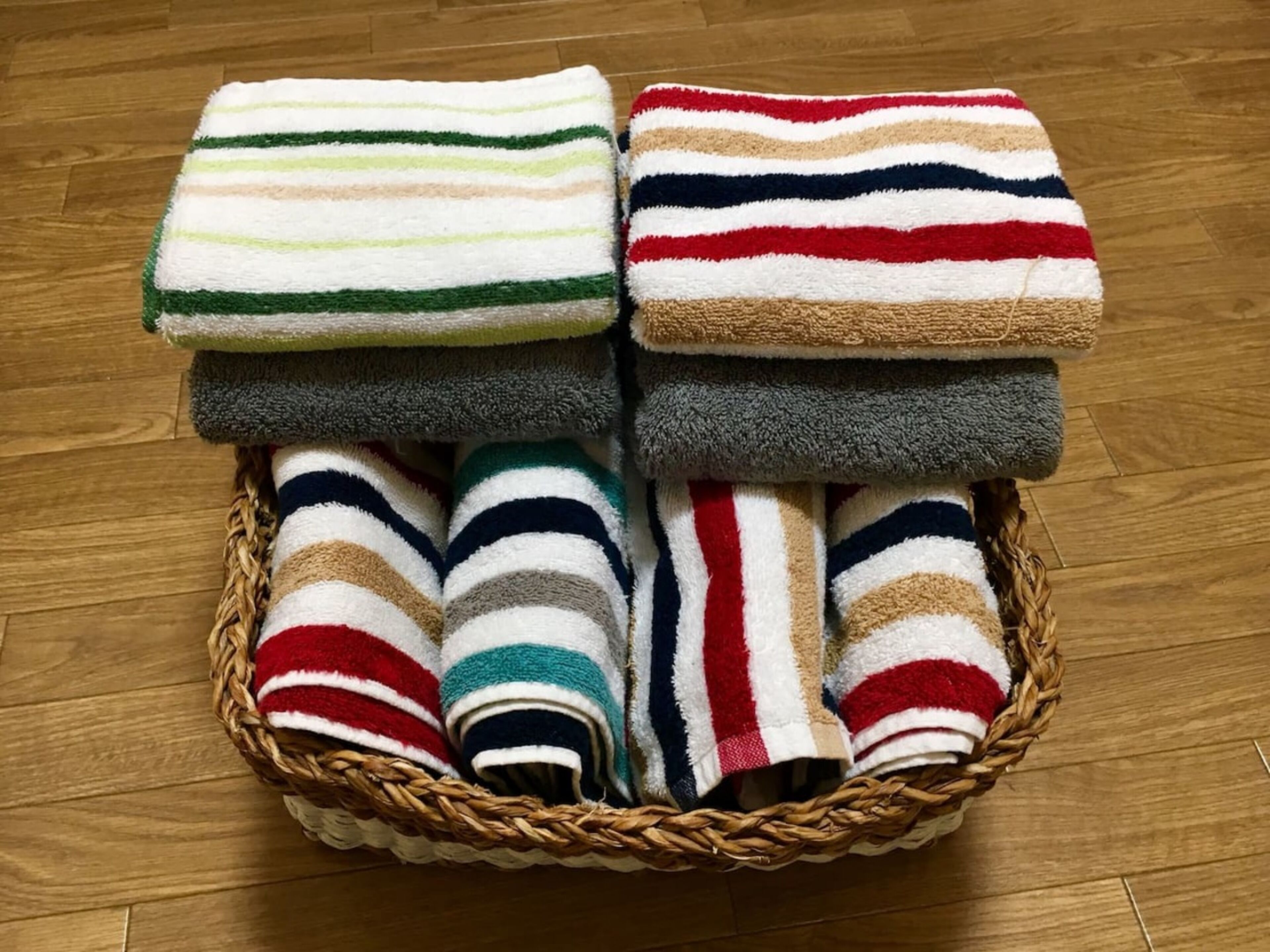 A basket containing folded towels with striped patterns in various colors.