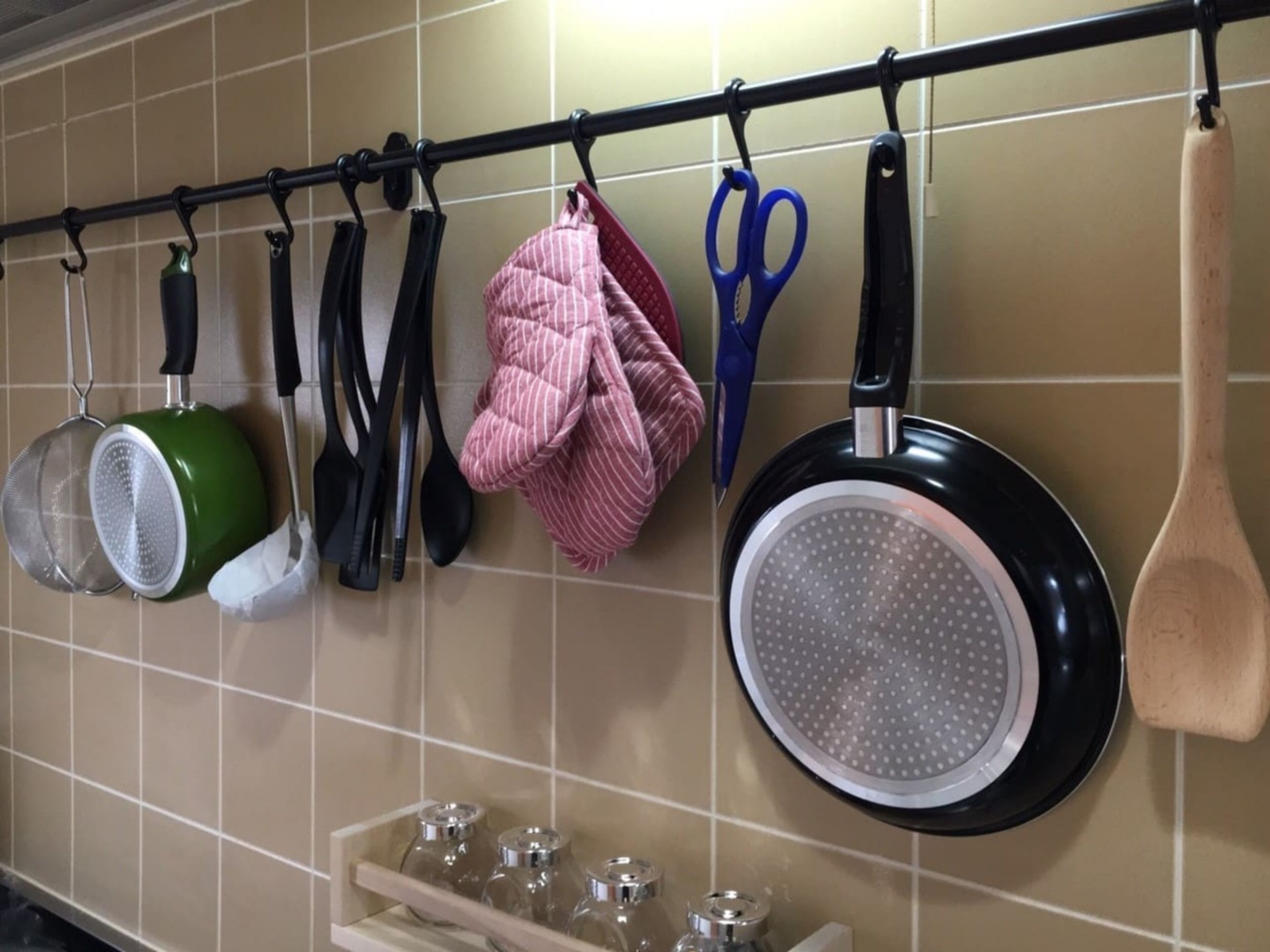 A kitchen with various utensils and cookware hanging on a rack.