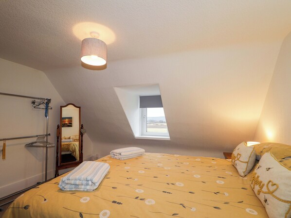 Une chambre à coucher avec un lit, une fenêtre, un luminaire suspendu et un miroir.