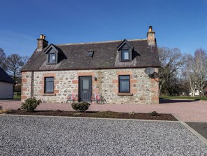 A stone house with a dark roof, two chimneys, a door, and two windows. - Nanville (Beauly)