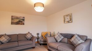 A living room with two sofas, a lamp, a clock, and a painting on the wall. - Nanville (Beauly)