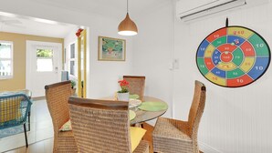 Un comedor con sillas de mimbre, una mesa de vidrio y una lámpara colgante.