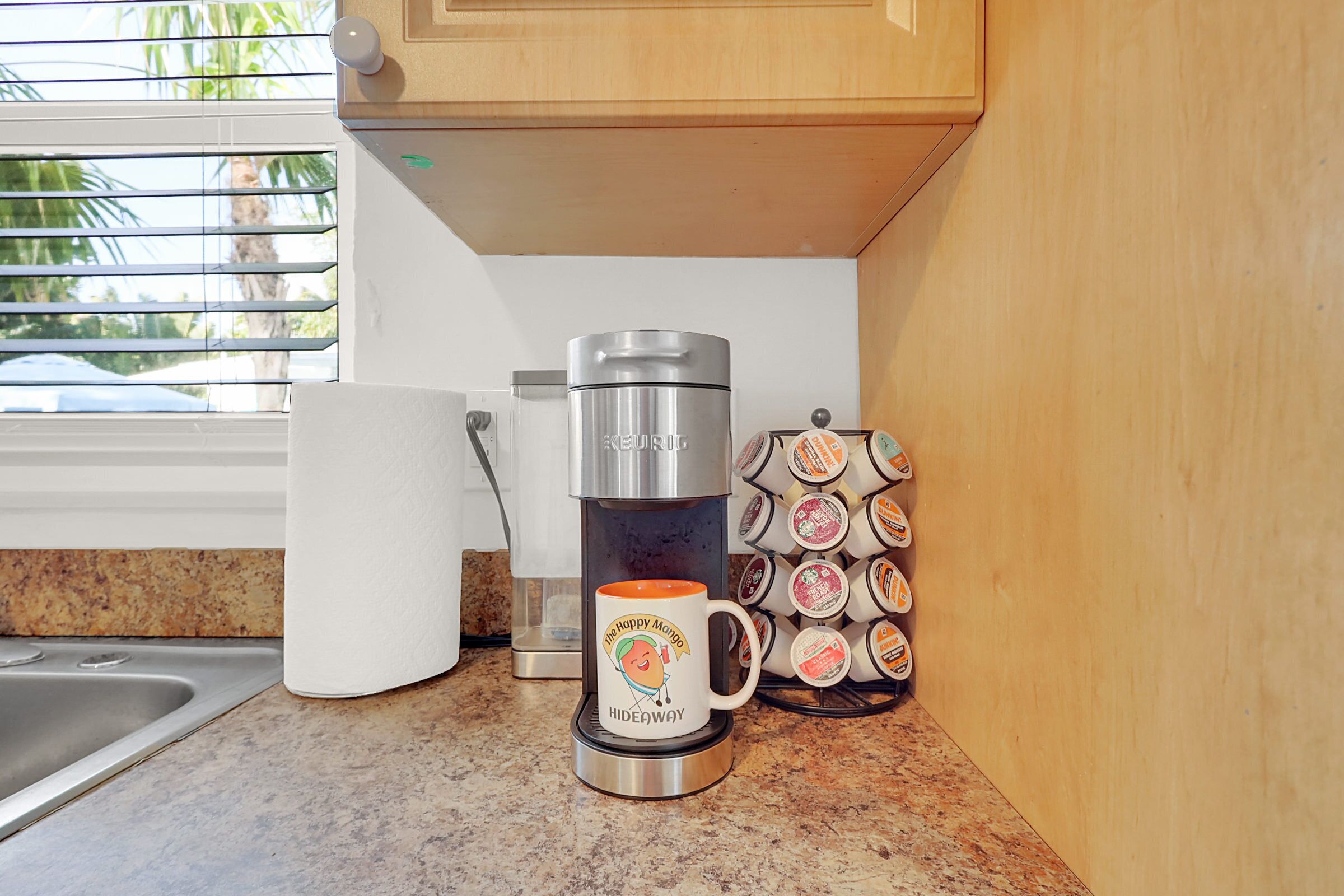 Una cocina con cafetera, taza y un soporte para tazas con varias opciones.