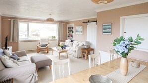 A living room with a sofa, armchairs, a coffee table, and a dining table. - Ty Bedw (Tyn-y-Gongl)