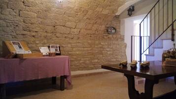 A room with a stone wall, a table with a checkered tablecloth, and a staircase.