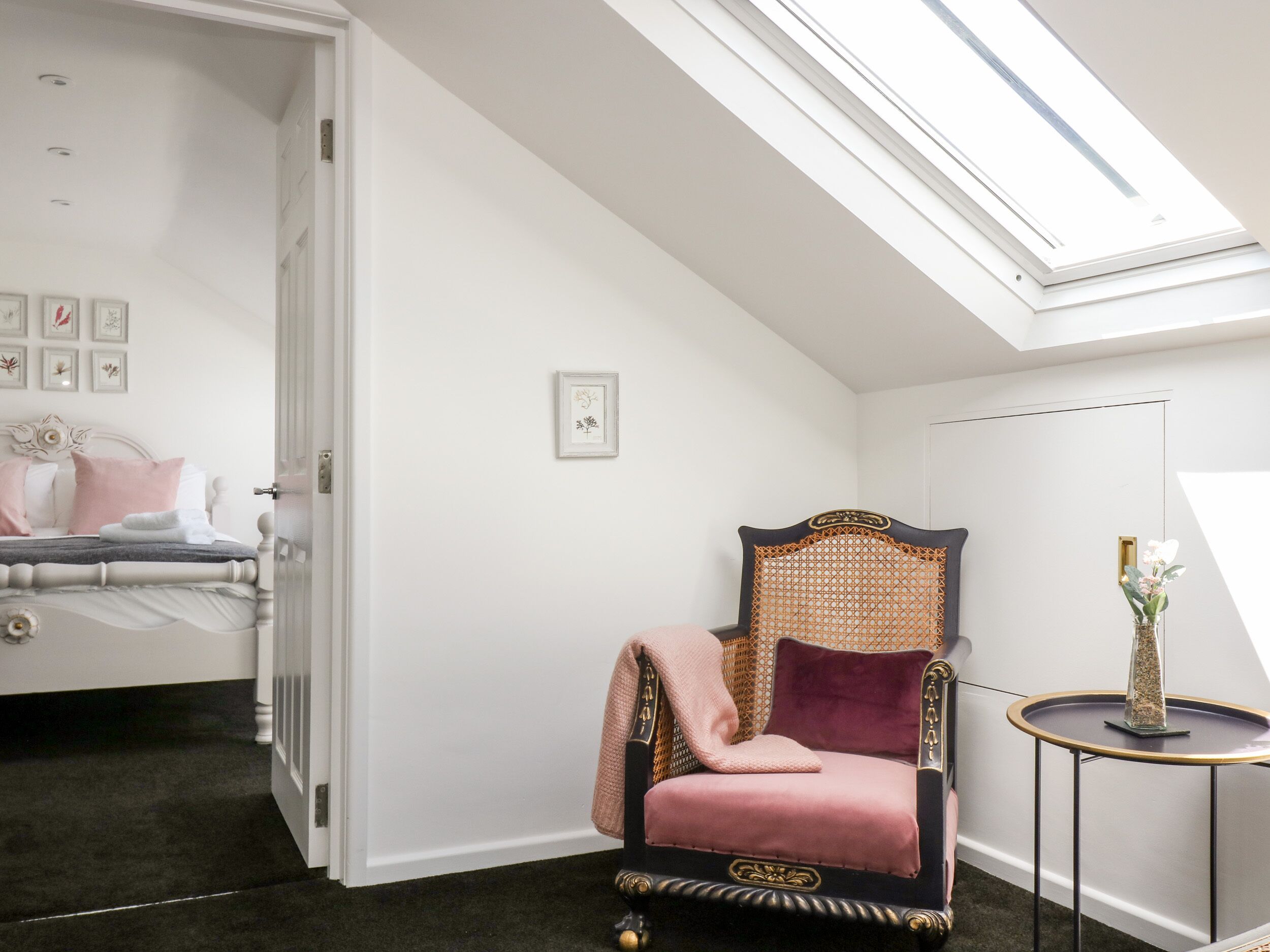 Une chambre à coucher avec un lit, une chaise, une petite table et une lucarne.