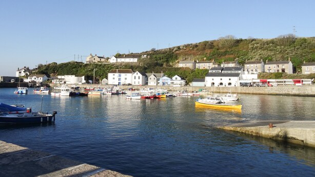 A harbor with boats docked, buildings along the shore, and a hill in the background. - Rock Pool House (Helston)