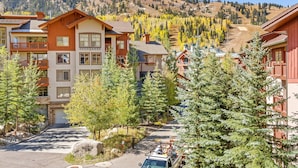 A residential area with multi-story buildings, a clear sky, and a mountainous backdrop. - First Tracks (with AC unit!) by Cottonwood Lodging (Solitude)