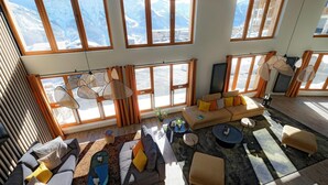 Amplia sala de estar con ventanas grandes, un conjunto de sofá, una mesa de centro y una alfombra.