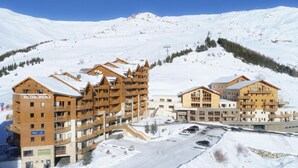 Un centro de esquí con edificios de madera, entre ellos un hotel llamado Rochebrune, con balcones y un telesilla al fondo.