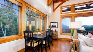A dining area with a wooden table and chairs, large windows with a view of trees, and a framed picture on the wall. - Breathtaking View - Fabulous & Well-Stocked Kitchen - Now renting for October🍁🍂🍁 (Boone)