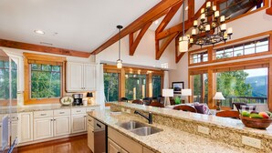 A spacious kitchen with granite countertops, wooden beams, and large windows offering views of the outdoors. - Breathtaking View - Fabulous & Well-Stocked Kitchen - Now renting for October🍁🍂🍁 (Boone)