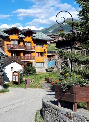 Un bâtiment traditionnel en bois, doté de balcons, d’un mur en pierre et d’une enseigne.