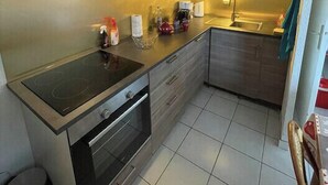 Eine kleine Küche mit eingebautem Herd, Backofen und Spüle.