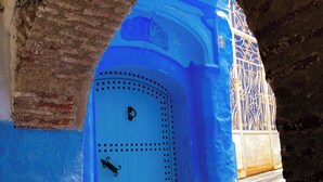 Une porte bleue avec une poignée en métal, encastrée dans un mur de pierre surmonté d’une arche en briques.