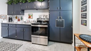 Cocina moderna con armarios oscuros, electrodomésticos de acero inoxidable y una salpicadera con el logo de NYC.