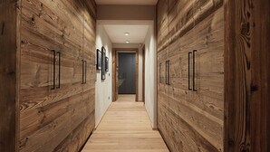 Um corredor estreito com paredes revestidas de madeira e piso de madeira, que leva a uma porta no final.