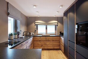 Eine moderne Küche mit Holzschränken, einer schwarzen Arbeitsplatte und einem Fenster mit Blick.