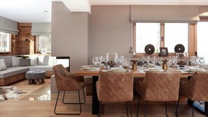 Uma sala de jantar moderna com uma mesa de madeira posta para seis pessoas, rodeada por seis cadeiras acolchoadas.