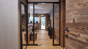 Ein modernes Interieur mit Holzboden, einer Küchenzeile mit Esstisch und Stühlen sowie einem großen Fenster mit Blick ins Freie.