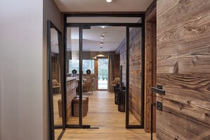 Ein modernes Interieur mit Holzboden, einer Küchenzeile mit Esstisch und Stühlen sowie einem großen Fenster mit Blick ins Freie.