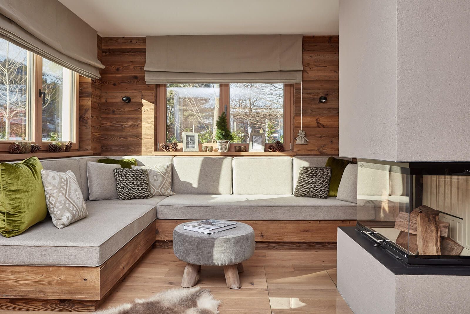 Una sala acogedora con un sofá modular, un reposapiés redondo y una chimenea.
