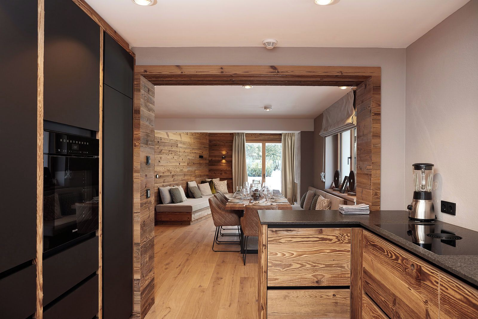 A modern kitchen with a wooden accent wall, a dining area with a sofa, and a kitchen island.