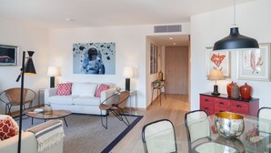 Una sala moderna con un sofá blanco, una mesa de comedor de vidrio y un mueble de almacenamiento rojo.