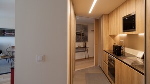 Una cocina moderna con armarios de madera, microondas integrado y encimera de acero inoxidable.