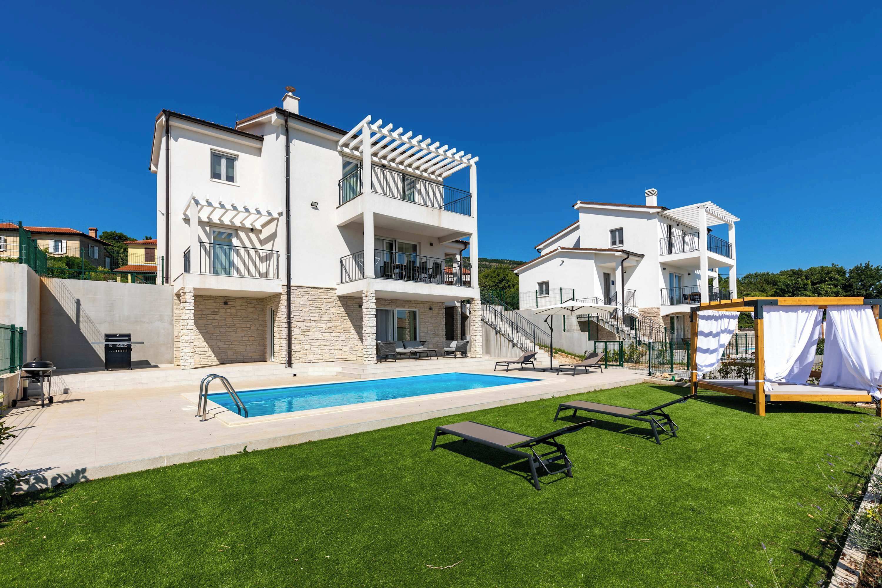 A two-story building with a swimming pool, outdoor seating, and a pergola.